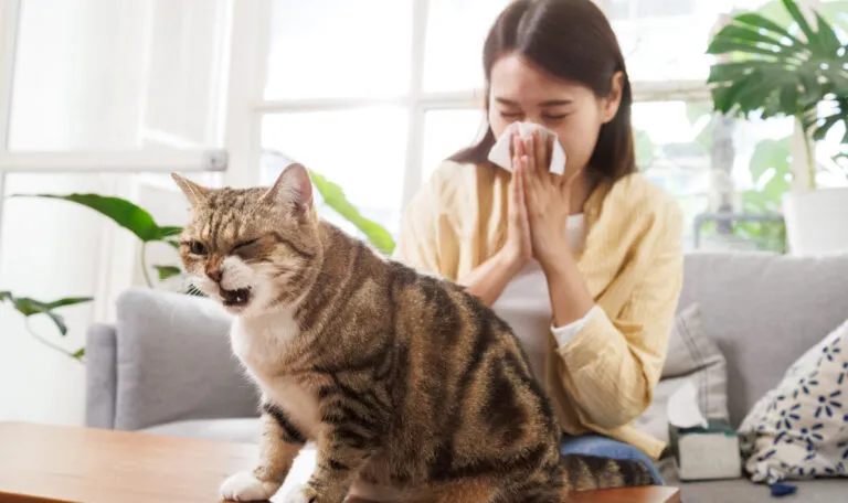 A woman and her cat sneezing.