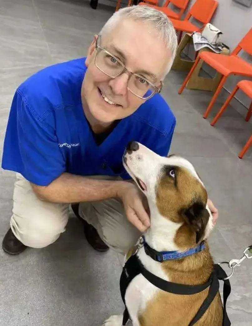 A veterinarian posing with a dog